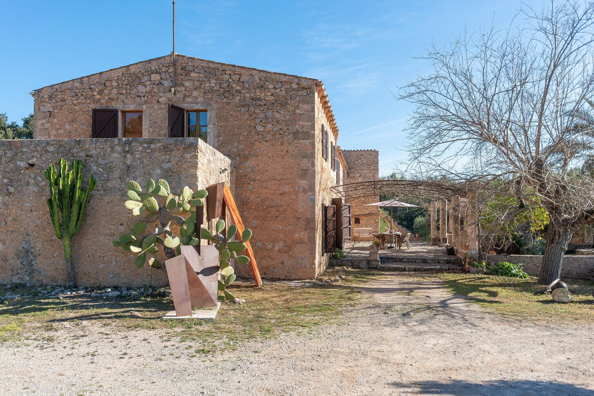 Un bâtiment rustique en pierre, avec un chemin de terre menant à une porte en bois.