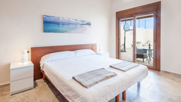 A bedroom with a large bed, a nightstand, a wall-mounted painting, and a sliding glass door leading to a balcony. - Cas Peix - Adults Only - Villa With Private Pool (Sa Pobla, Illes Balears)