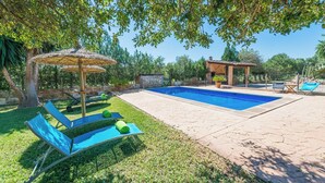 A backyard with a swimming pool, lounge chairs, and a pergola.