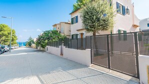 A residential street with houses, a tree, and a metal fence. - El Pinar - Villa With Private Pool. Free Wifi (Cala Sant Vicenç, Illes Balears)