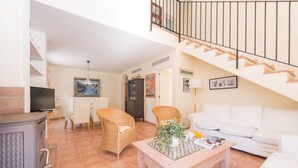 A living room with a sofa, two wicker chairs, a coffee table, a TV, and a fireplace. - El Pinar - Villa With Private Pool. Free Wifi (Cala Sant Vicenç, Illes Balears)