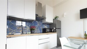 A modern kitchen with white cabinets, a marble backsplash, a coffee machine, and a TV mounted on the wall. - Peace window, al centro del centro di Roma e d'Italia (Roma)