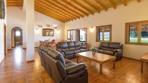 Ein geräumiges Wohnzimmer mit Ledersofas, einem Holztisch und einer Essecke mit Stühlen und Tisch.