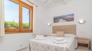 Une chambre à coucher avec un lit, une table de chevet, une fenêtre et un tableau accroché au mur.