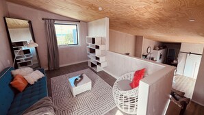 A modern bedroom with a large window, a blue sofa, a white dresser, and a white wardrobe. - “ VITAMIN SEA “ 
Beach ~ House  (Riverton / Aparima)