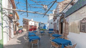 An outdoor café with tables and chairs, surrounded by buildings with various signs and decorations. - Cascades - Apartment In Dénia (Denia, Alicante)