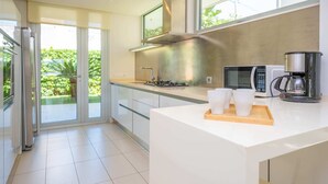 Een moderne keuken met een groot schiereiland, roestvrijstalen apparatuur en een schuifdeur naar een balkon.