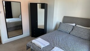 A bedroom with a bed, a large mirror, and a wardrobe. - Home and Away (Eaglescliffe)
