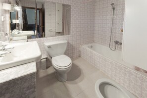 Une salle de bain avec des toilettes, un lavabo et une baignoire.