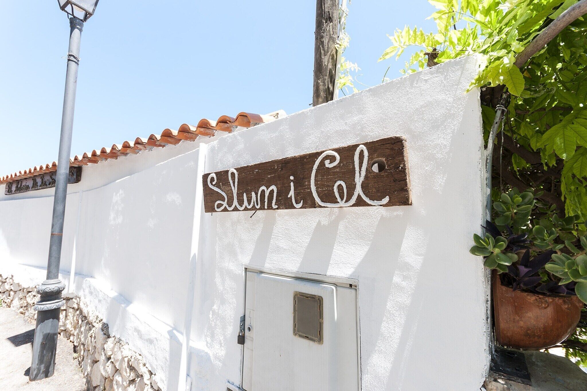 A white wall with a wooden sign that reads "Slumi Col."