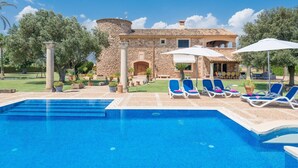 A pool area with lounge chairs and umbrellas, a stone building with arches, and a clear blue sky. - Can Colis - Villa With Private Pool In Sa Pobla (Sa Pobla, Illes Balears)