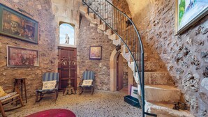 A stone-walled room with a spiral staircase, wooden furniture, and artwork. - Can Colis - Villa With Private Pool In Sa Pobla (Sa Pobla, Illes Balears)