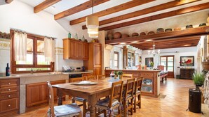 A spacious kitchen with wooden cabinets, a large dining table, and a tiled floor. - Can Colis - Villa With Private Pool In Sa Pobla (Sa Pobla, Illes Balears)