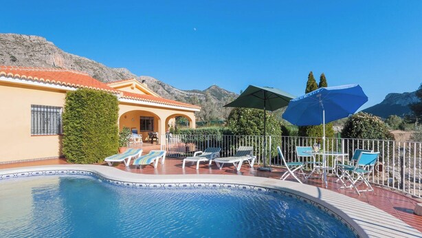 A swimming pool with lounge chairs and a table, surrounded by a white fence, with mountains in the background. - Portilet - Villa With Private Pool In Barx (Barx, Valencia)
