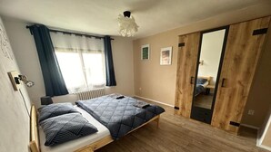 Un dormitorio con dos camas, suelo de madera, un radiador y un espejo grande.