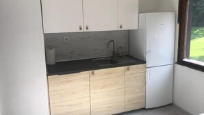Una cocina compacta con armarios blancos, una encimera negra y un lavabo integrado.
