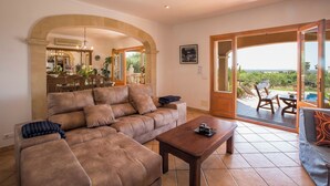 Ein geräumiges Wohnzimmer mit einem großen Sofa, einem Couchtisch und Blick auf eine Poolterrasse.