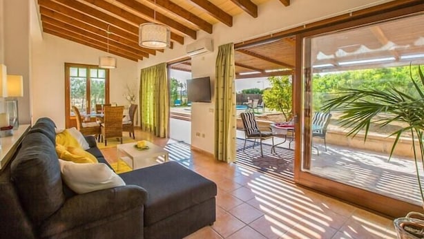 A spacious living area with a sofa, dining table, and chairs. Large windows provide natural light and a view of the outdoors. - Shostalet - Villa With Private Pool In Algaida (Algaida, Illes Balears)