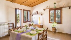 A dining area with a table set for four, wooden chairs, a radiator, and a potted plant. - Shostalet - Villa With Private Pool In Algaida (Algaida, Illes Balears)