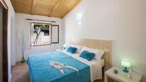A bedroom with a wooden ceiling, a bed with a blue bedspread, white pillows, and a nightstand with a lamp. - Shostalet - Villa With Private Pool In Algaida (Algaida, Illes Balears)