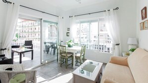 Ein helles Wohnzimmer mit einer Couch, einem Esstisch mit Stühlen und einem Couchtisch mit Glasplatte.
