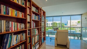 Eine Bibliothek mit Bücherregalen und Blick ins Freie durch große Fenster.