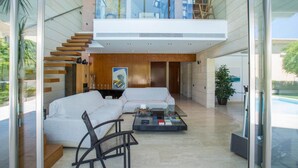Ein modernes Wohnzimmer mit einem Glastisch, einem weißen Sofa und einer Treppe, die in eine obere Etage führt.