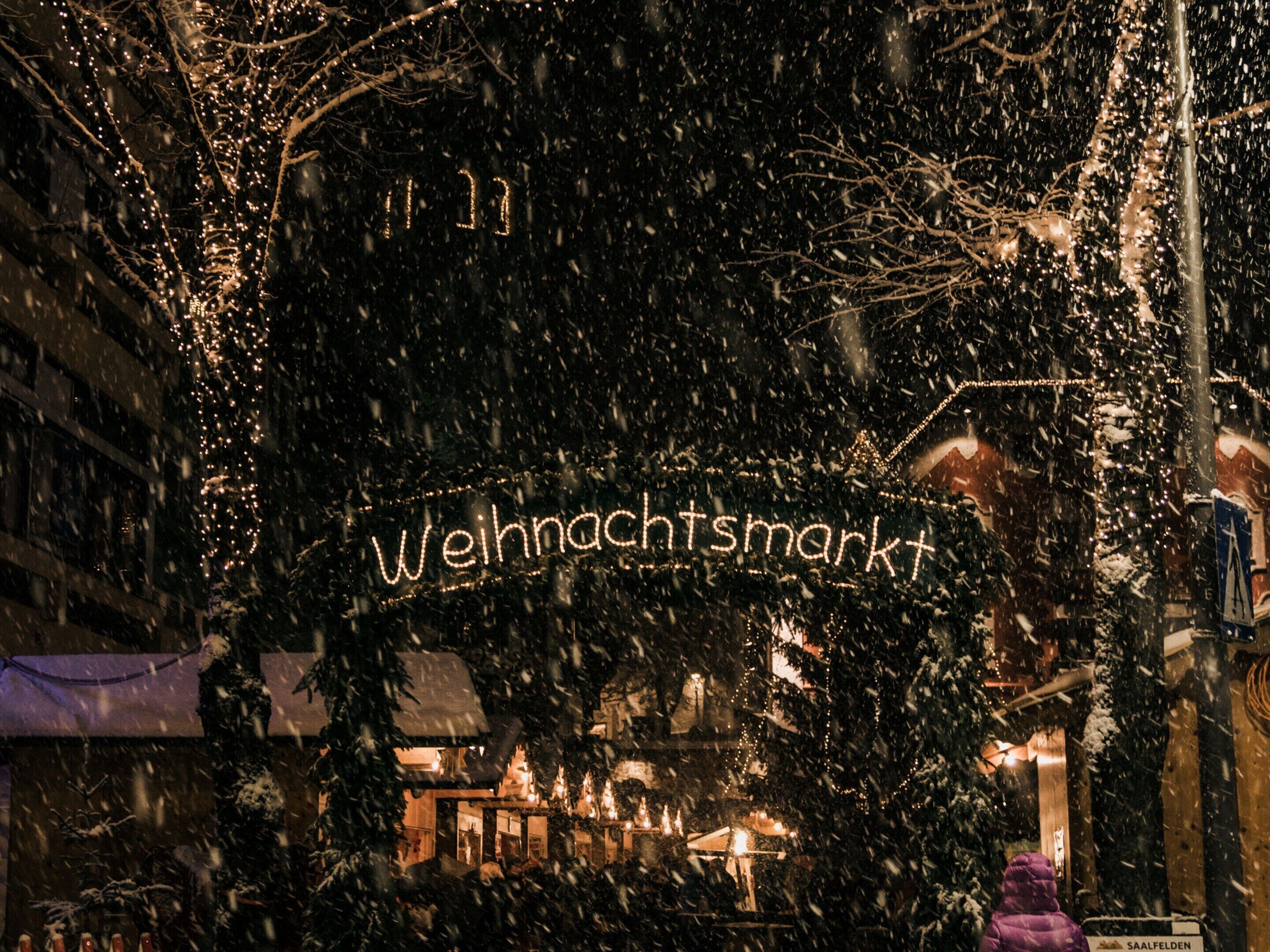 A snow-covered street with illuminated signs reading "Weihnachtsmarkt" and "SAALFELDEN".