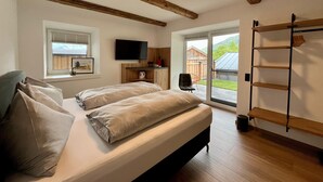 A bedroom with a bed, a TV, a window, and a view of the outdoors. - Apartment in Saalfelden Near Ski Slopes (Saalfelden am Steinernen Meer)