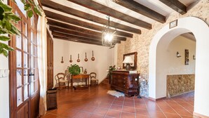 A rustic interior with exposed wooden beams, a tiled floor, and a stone wall.
