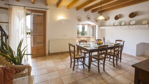Zona pranzo con tavolo e sedie in legno, una pianta in vaso e una finestra vista.