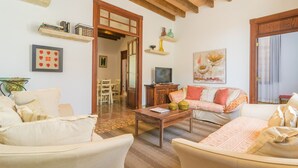 Una sala de estar acogedora con techo de madera, televisor y sofá con cojines estampados.