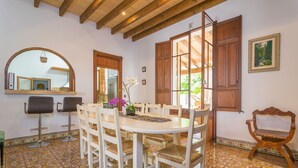 Un comedor con una mesa redonda, sillas blancas y un banco de madera.