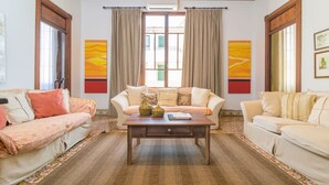 Una habitación con dos sofás, una mesa de centro de madera y un ventanal con cortinas.
