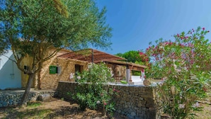 A stone house with a tiled roof, surrounded by a stone wall and a garden with flowering plants. - Sa Rota (den Joan Porrerenc) - Apartment (MontuÏri, Illes Balears)