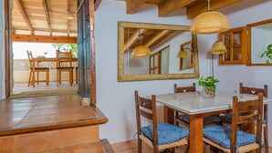 A dining area with a wooden table and chairs, a mirror, and hanging lamps. - Sa Rota (den Joan Porrerenc) - Apartment (MontuÏri, Illes Balears)