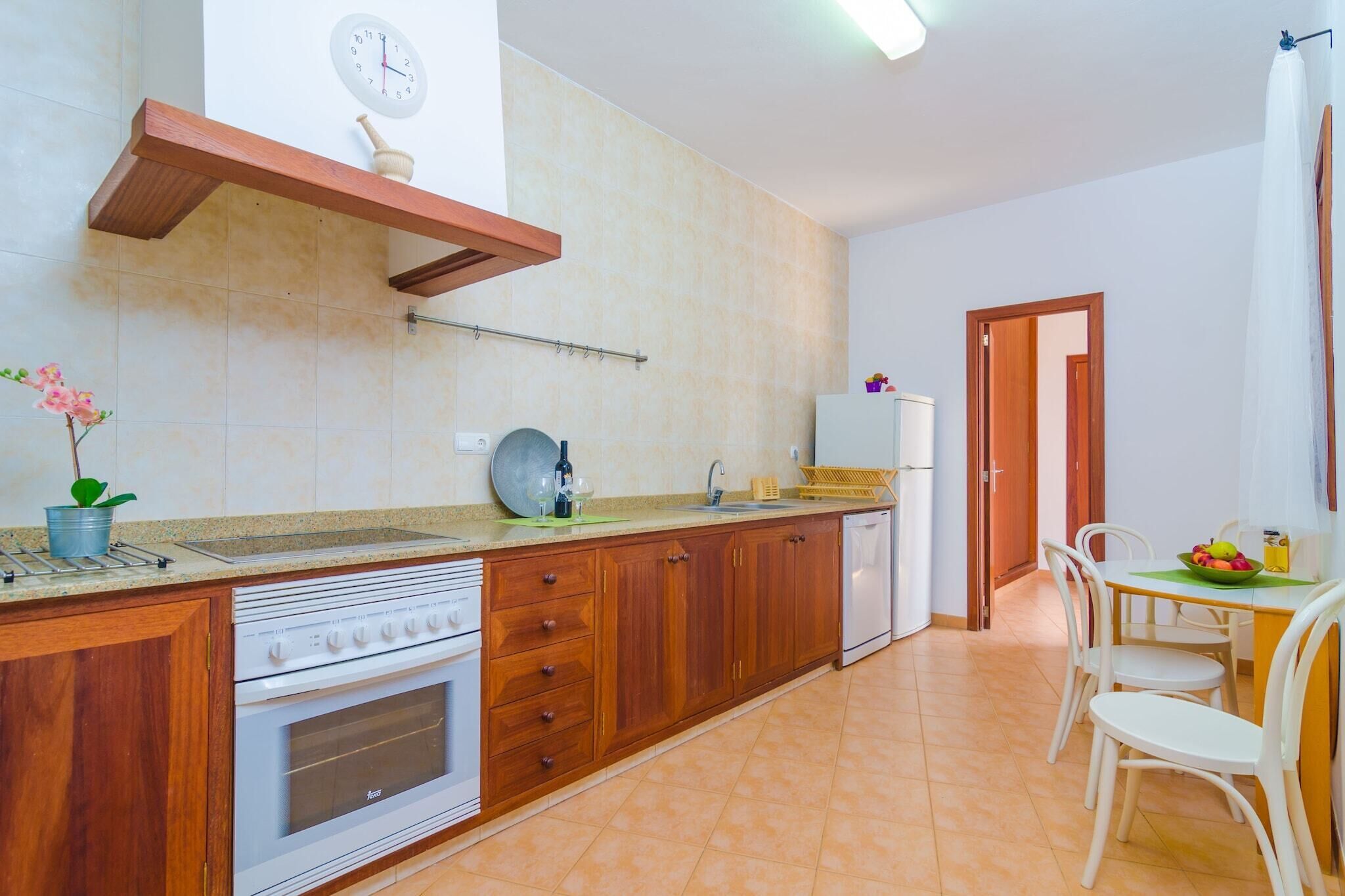 A kitchen with wooden cabinets, a built-in oven, a sink, and a dining area with a table and chairs.