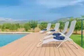 Un espace aménagé au bord de la piscine, avec des chaises longues et une vue sur le paysage.