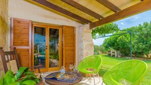 Un área de estar al aire libre con techo, muebles de madera y una mesa con vasos y un menú.