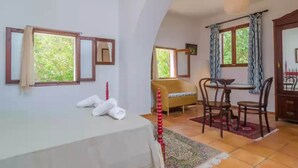 A room with a bed, a dining table with chairs, a sofa, and a window with curtains. - Can Bolei - Villa With Private Pool In Sant Elm (Sant Elm (andratx), Illes Balears)
