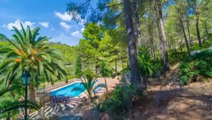 A pool area surrounded by lush greenery and trees, with a clear blue sky above. - Can Bolei - Villa With Private Pool In Sant Elm (Sant Elm (andratx), Illes Balears)