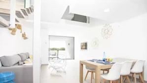 A modern, minimalist living space with a dining area and a staircase. - S'aigua 5 - Villa With Private Pool In S'illot (S'illot, Illes Balears)