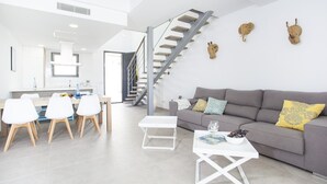 A modern living space with a staircase, a dining area, and a sofa. - S'aigua 5 - Villa With Private Pool In S'illot (S'illot, Illes Balears)