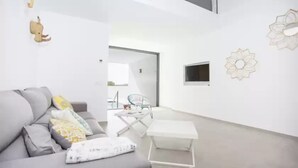 A modern living room with a grey sofa, a small white table, and decorative wall art. - S'aigua 5 - Villa With Private Pool In S'illot (S'illot, Illes Balears)