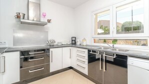 A modern kitchen with stainless steel appliances, white cabinetry, and a large window providing a view of the outdoors. - Xalet S'escaleta - Villa With Private Pool (Cala Santanyí, Illes Balears)
