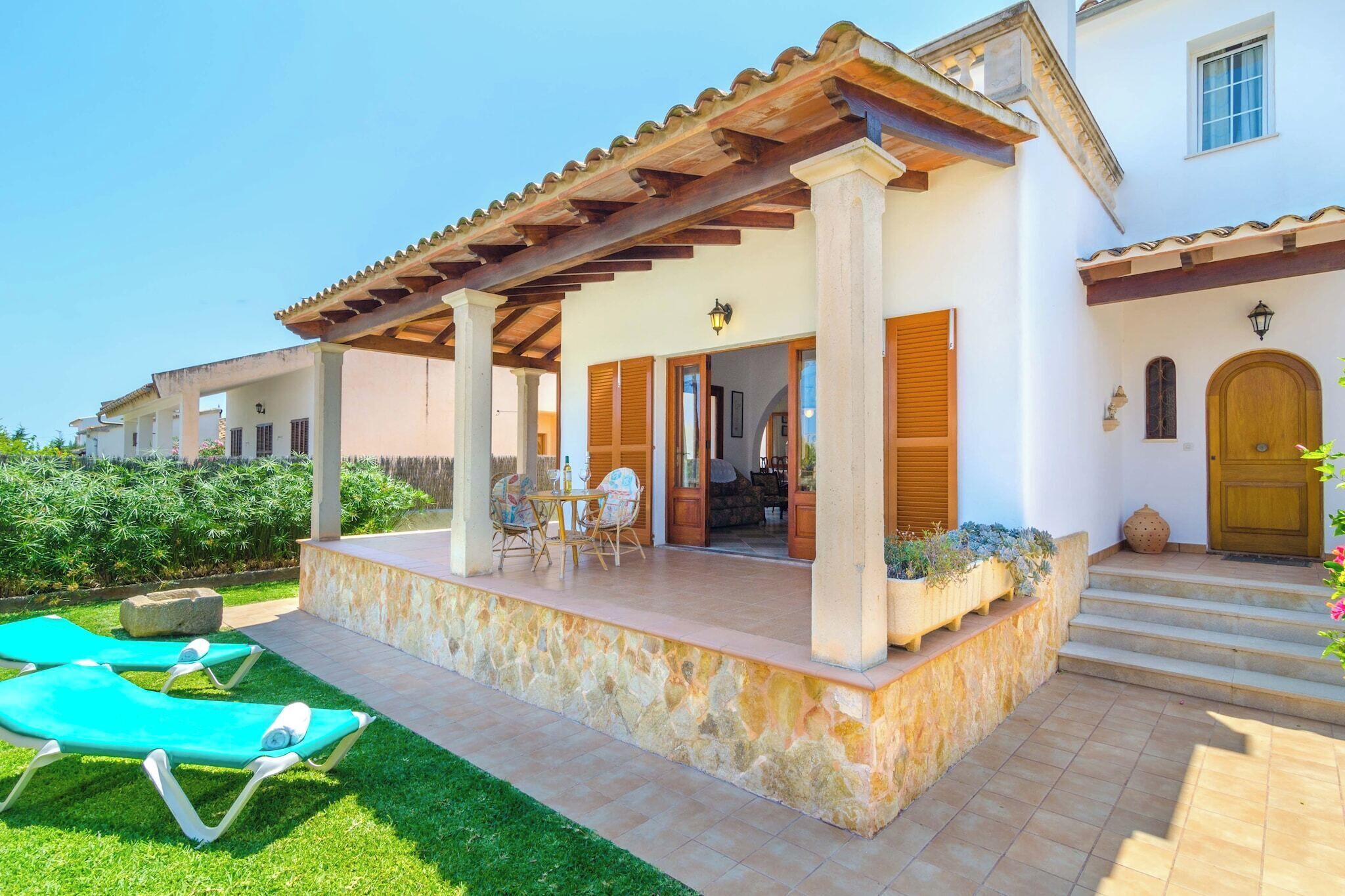 A covered outdoor area with a stone platform, lounge chairs, and a pergola.
