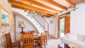 Una habitación acogedora con una escalera de madera, un comedor con mesa y sillas, y un sofá.