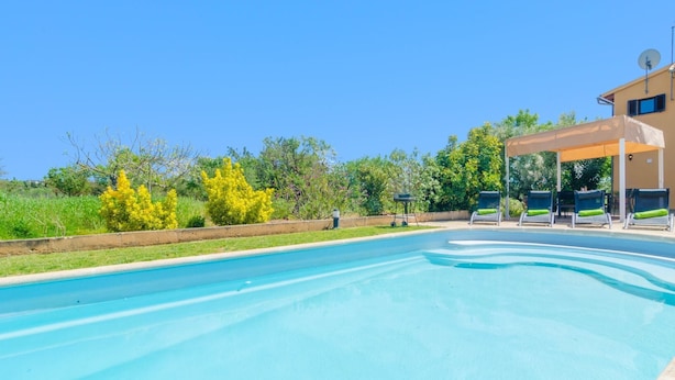 A swimming pool with lounge chairs and a covered area, surrounded by greenery and a building. - S'alqueria - Villa With Private Pool In Campanet (Campanet, Illes Balears)