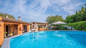 A clear blue swimming pool with a lifeguard chair, a lifebuoy, and a covered seating area with a table and chairs. - Finca Can Calisto - Apartment With Private Pool (Inca, Illes Balears)