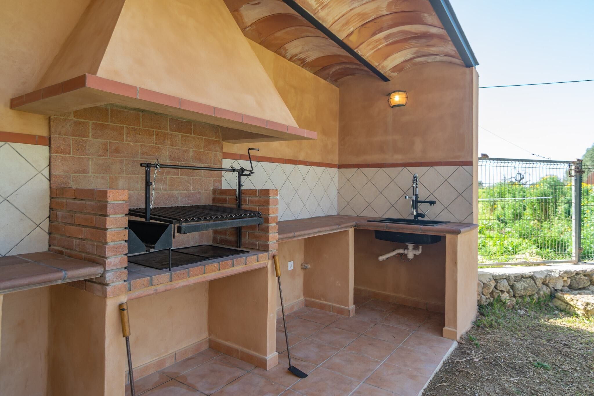 An outdoor kitchen with a brick oven, a sink, and a pergola structure.
